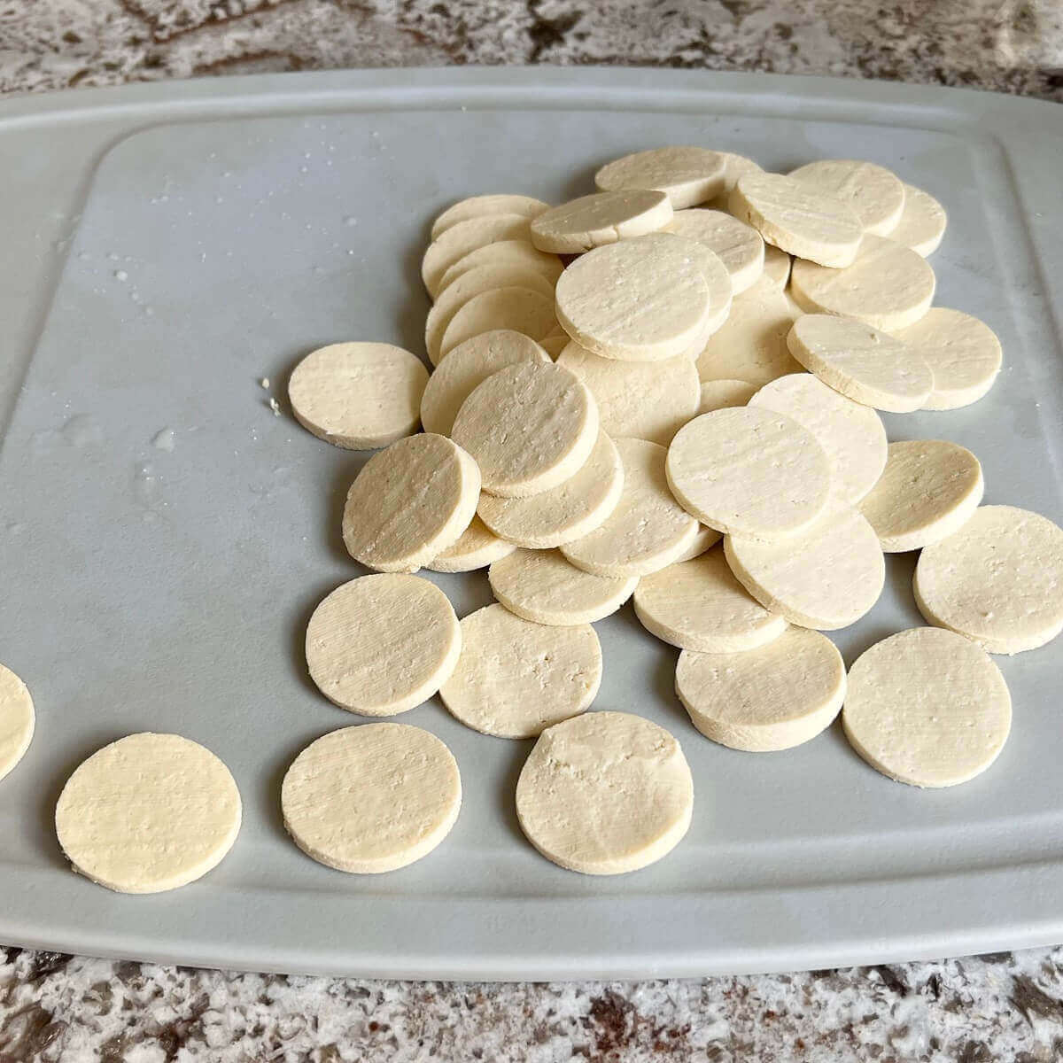 Tofu cut in circle shapes on a cutting board.