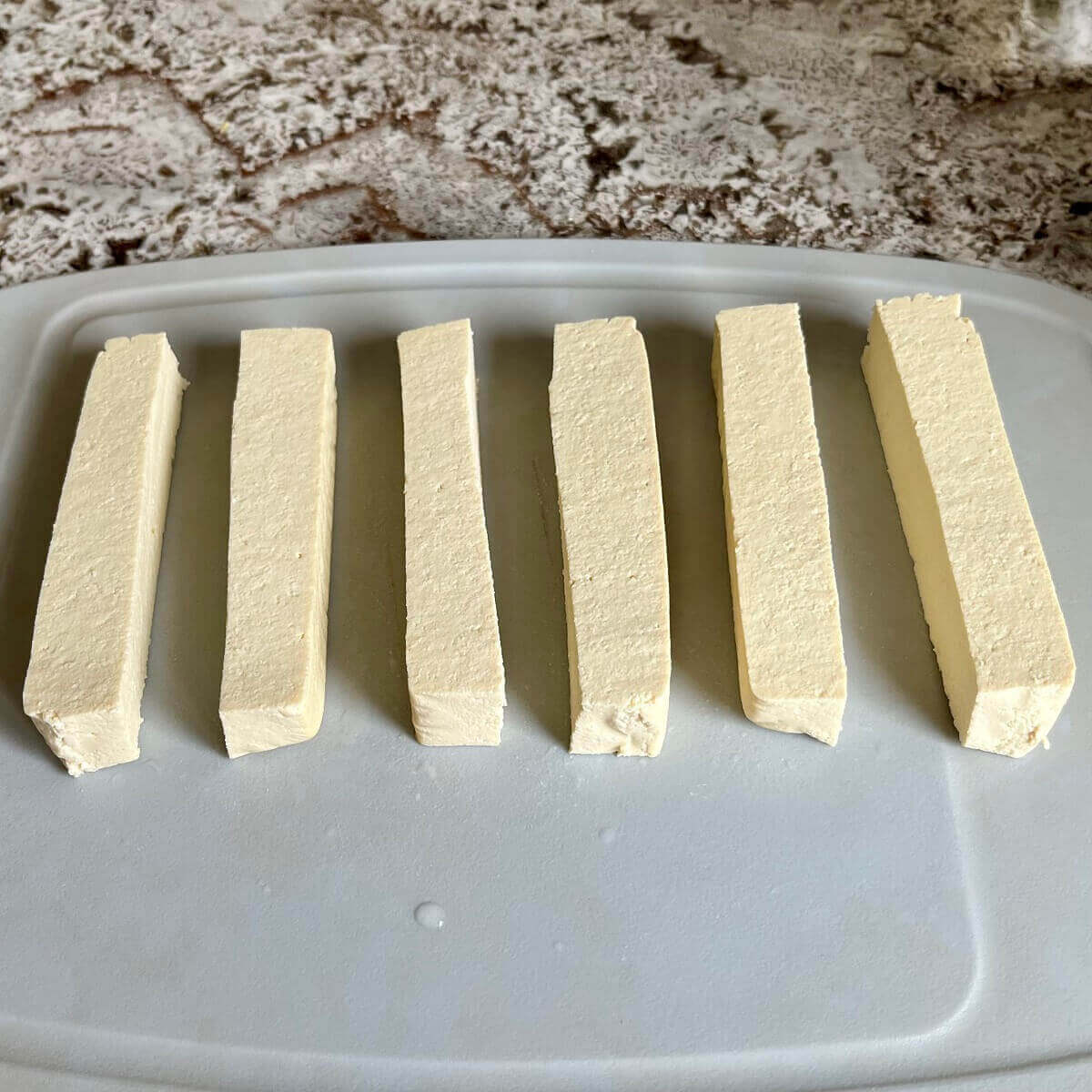Rectangle shaped tofu slices on a cutting board.