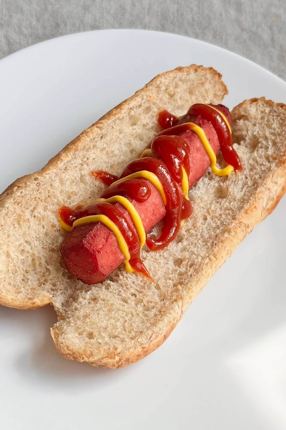 A vegan hot dog on a white plate.