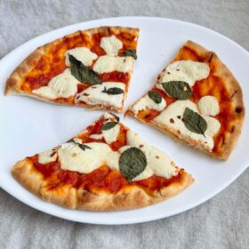 A pizza with vegan liquid mozzarella, tomato sauce, and basil leaves.
