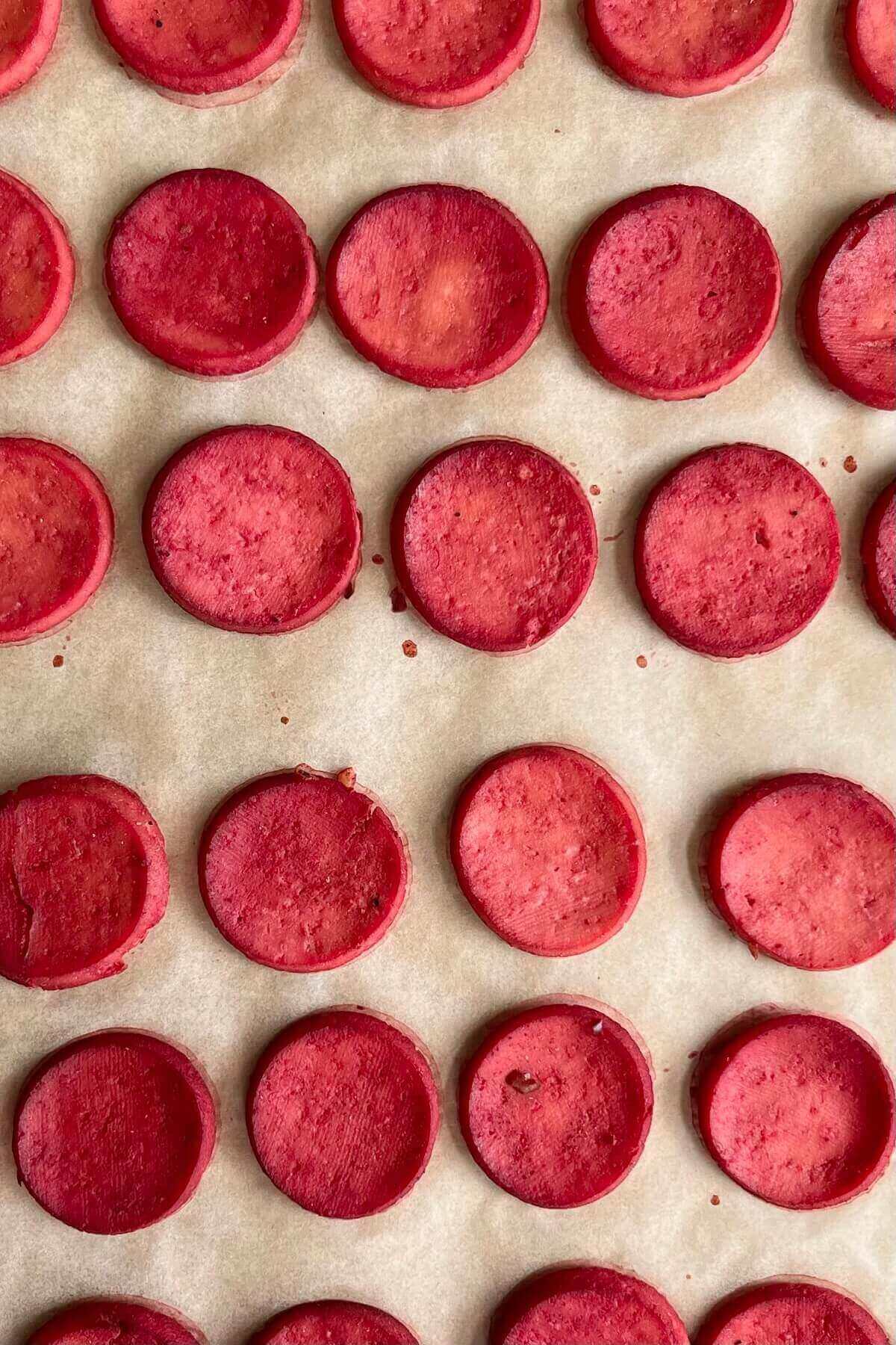 Cooked vegan pepperoni on a sheet pan lined with parchment paper.
