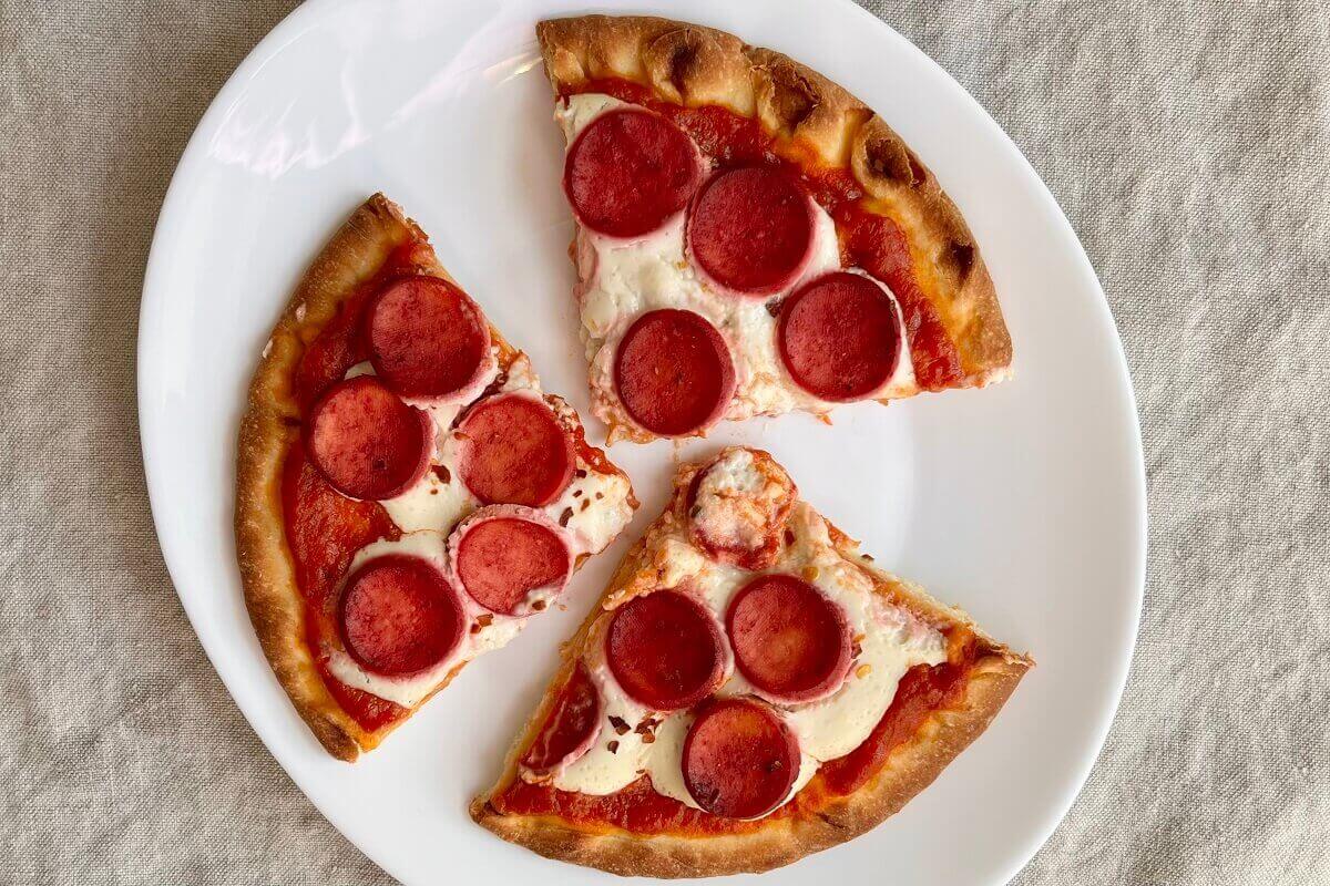 Vegan pizza with pepperoni on a white plate.