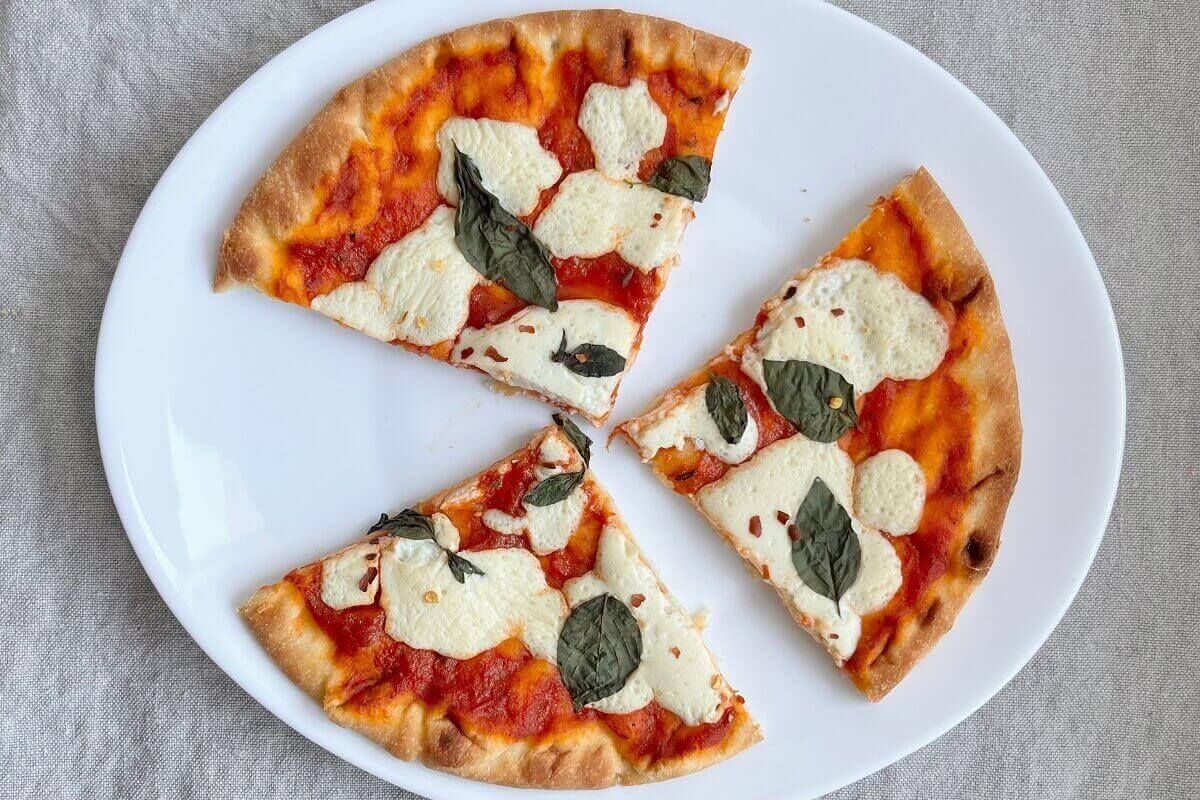 Three slices of vegan pizza on a white plate.