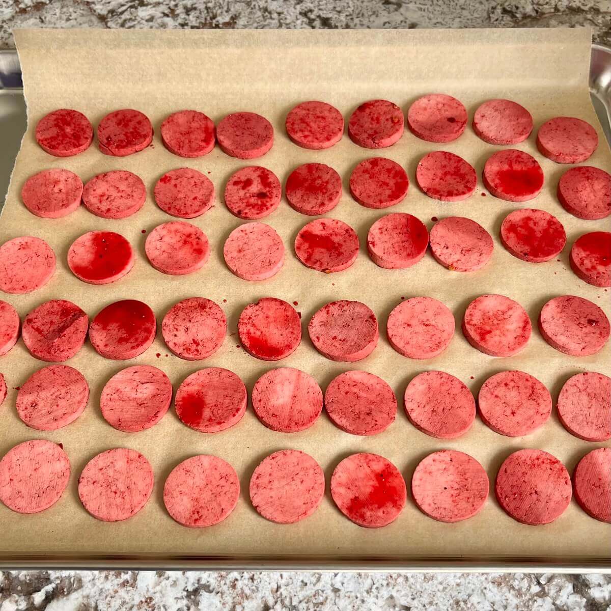 Vegan raw pepperoni slices on a sheet pan lined with parchment paper.