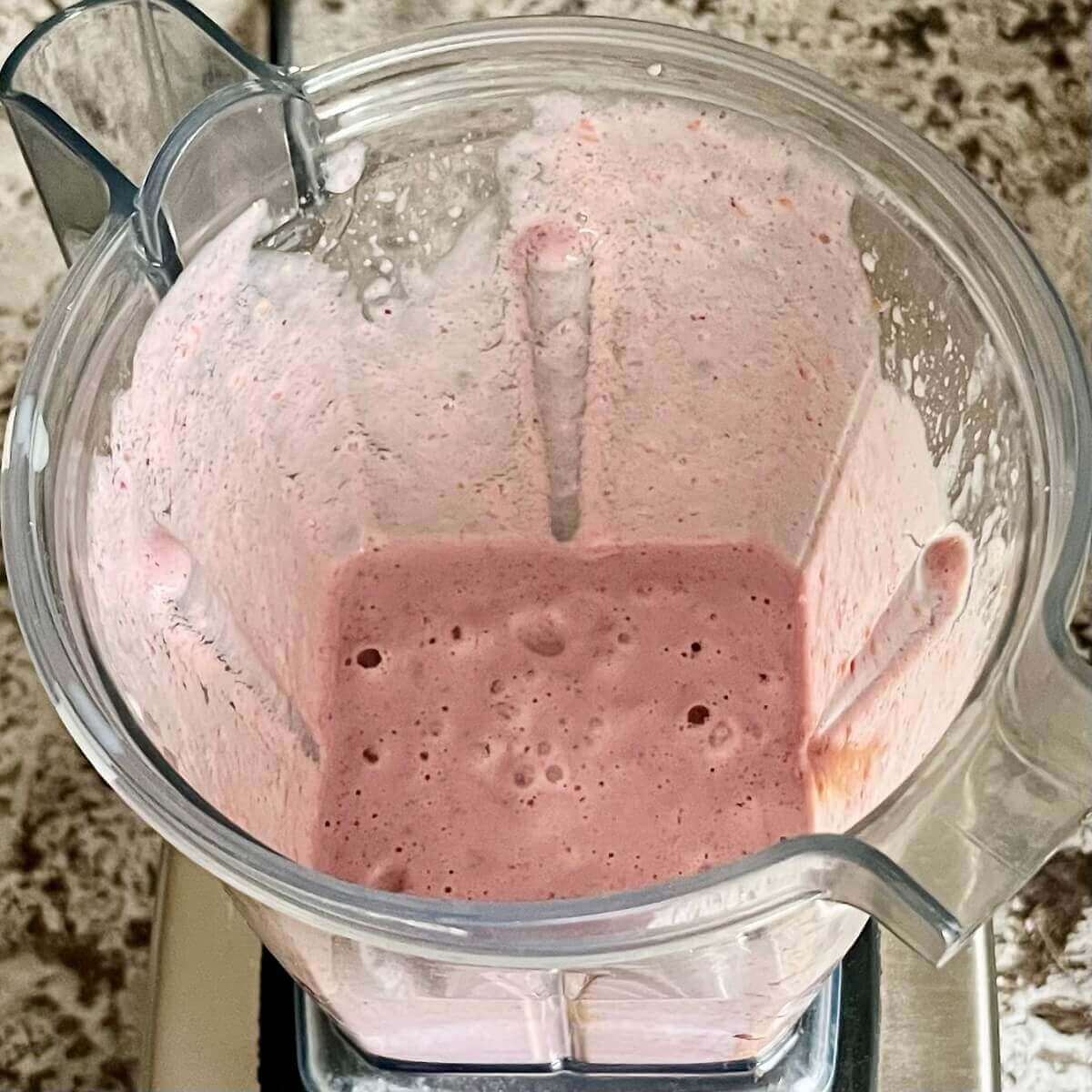 Blended raspberries, peanut butter, and other smoothie ingredients in a blender.