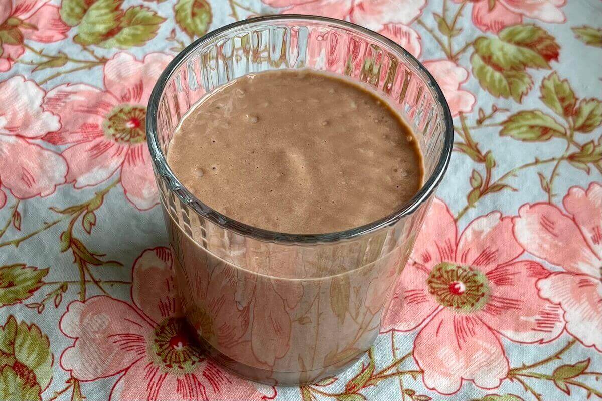 A creamy brown smoothie in a glass.