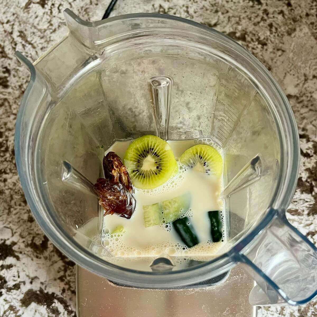 Chopped cucumbers, kiwi, a date, sea salt, and soy milk in a blender.