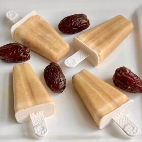 Date popsicles and dates on a white platter.
