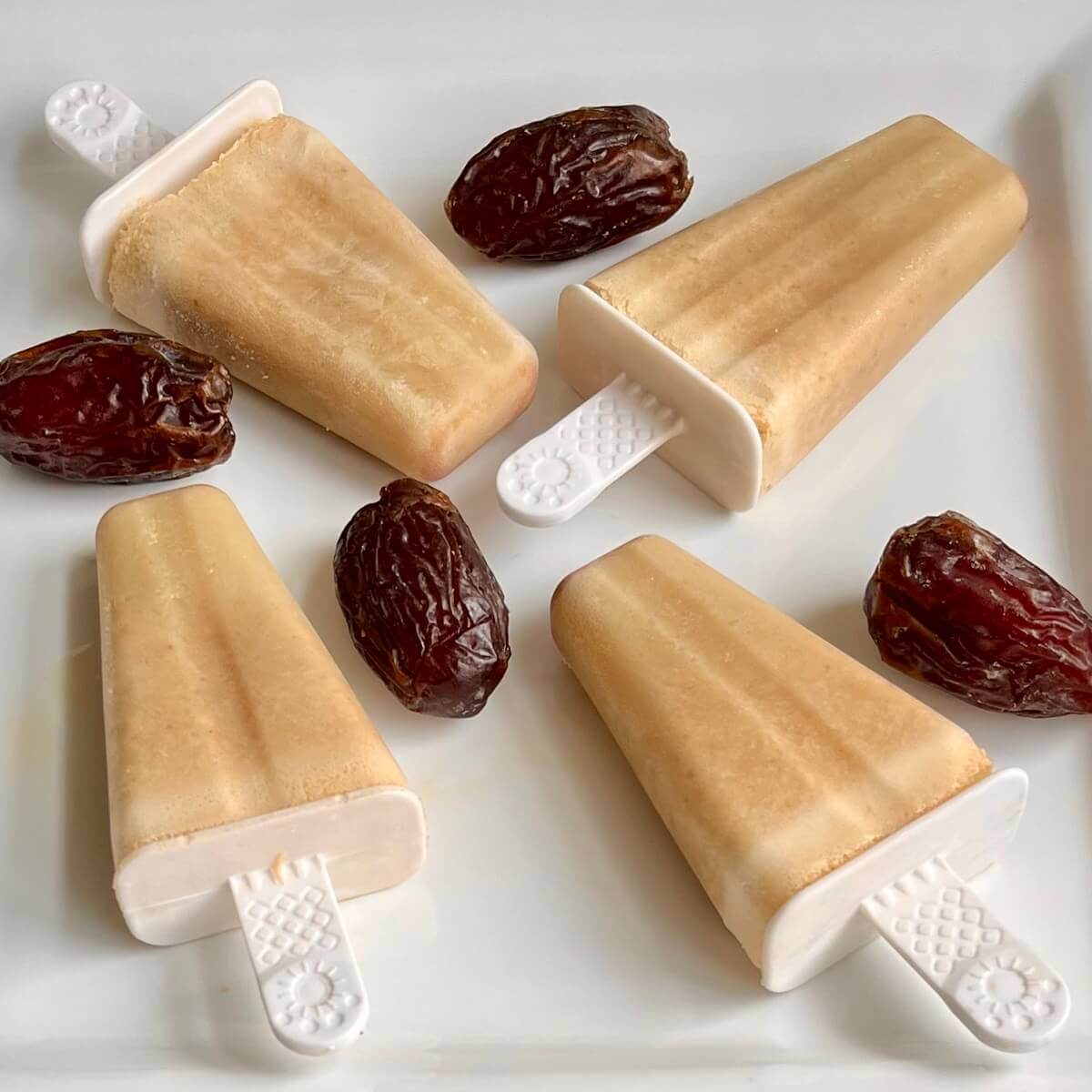 Date popsicles and dates on a white platter.
