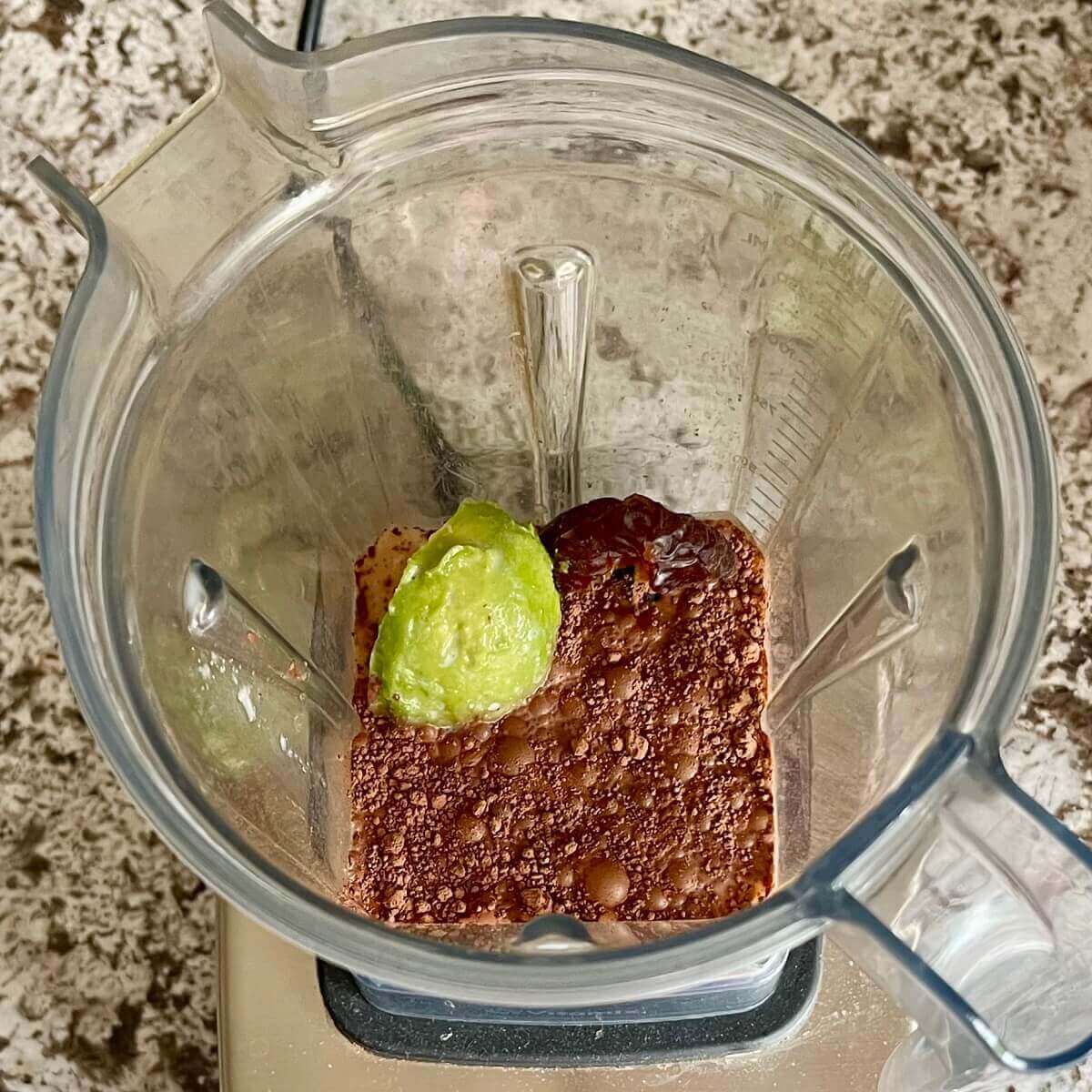 Dates, avocado, and other ingredients for a smoothie in a blender.