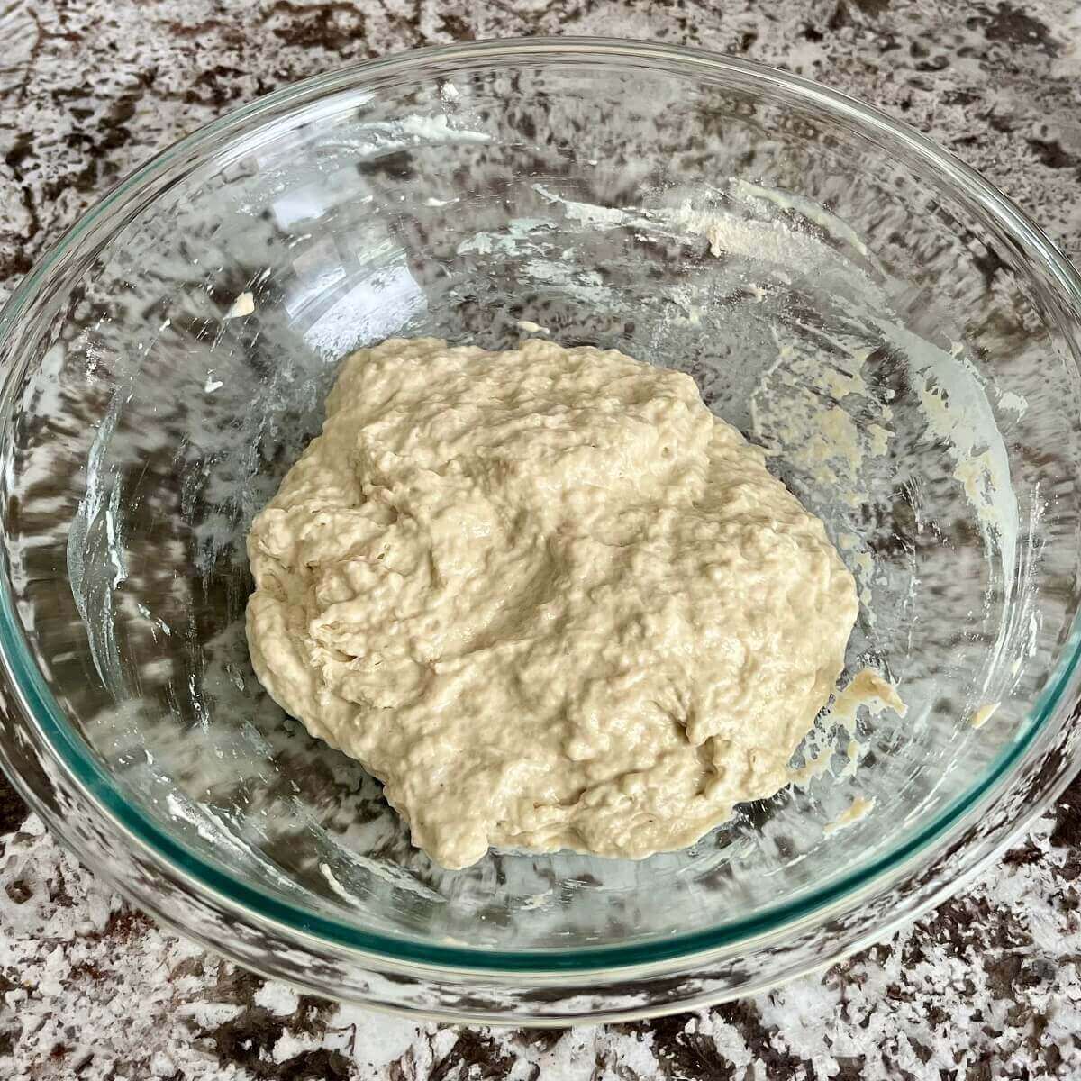 Bread dough in a large glass mixing bowl.