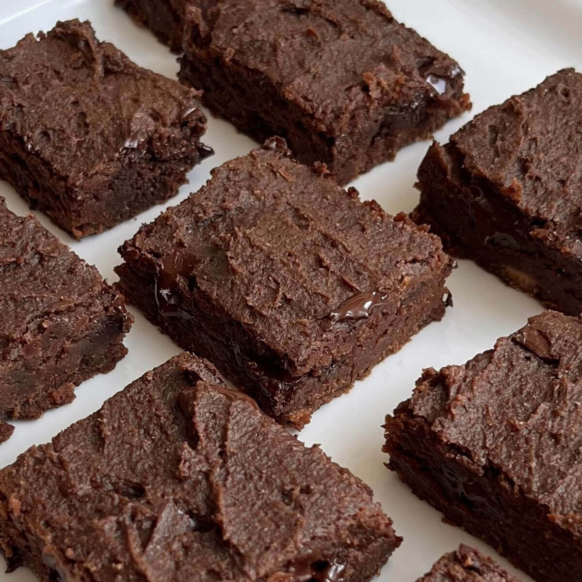 Lentil brownies cut in squares on a white plate.