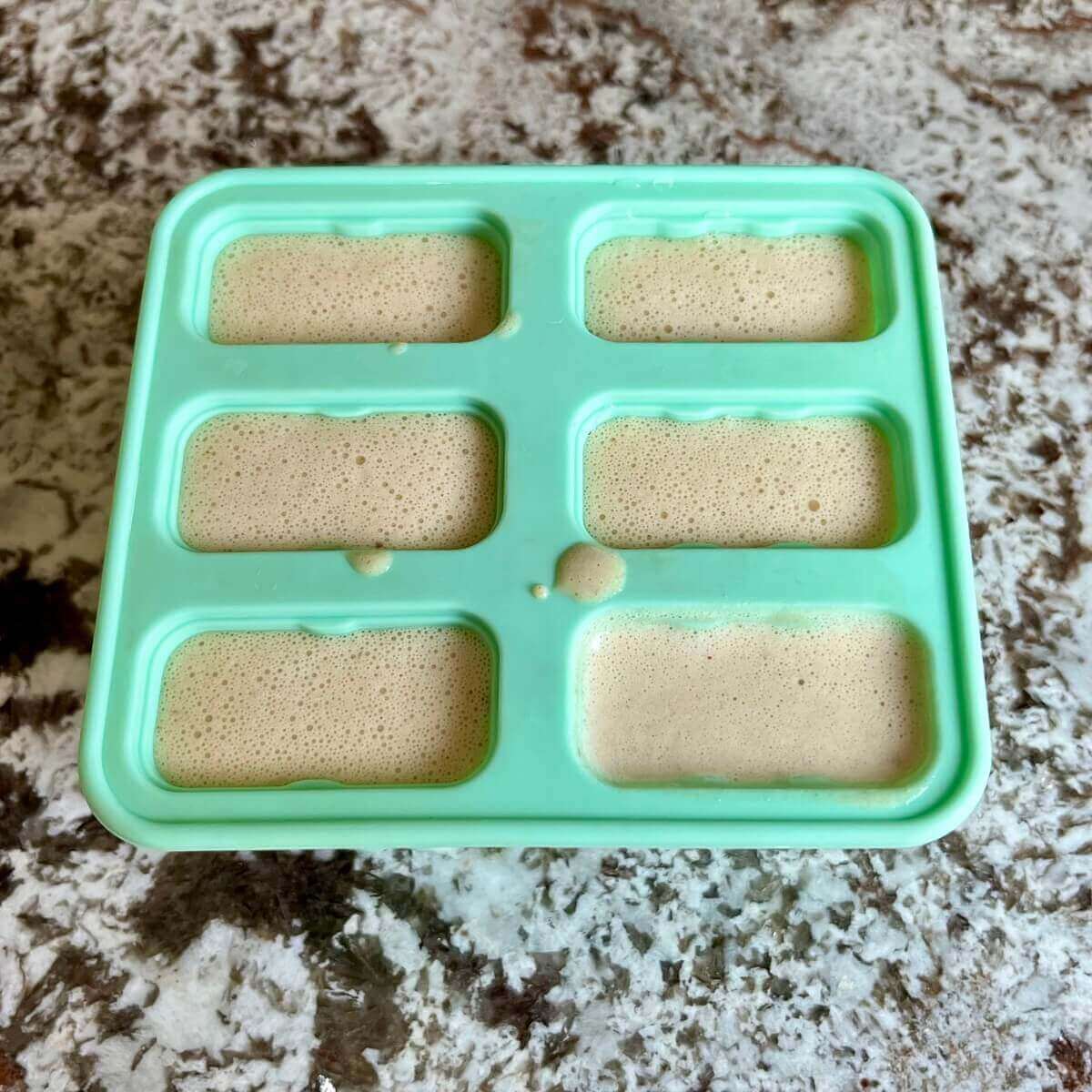 Light brown liquid in a popsicle mold.