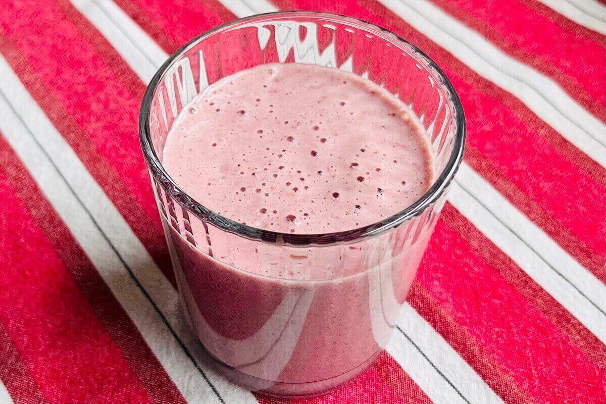 A creamy pink smoothie in a glass.