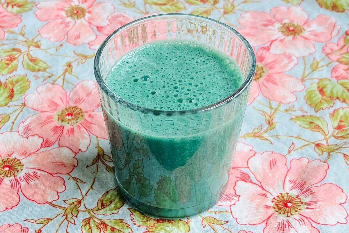 A bright turquoise smoothie in a glass.