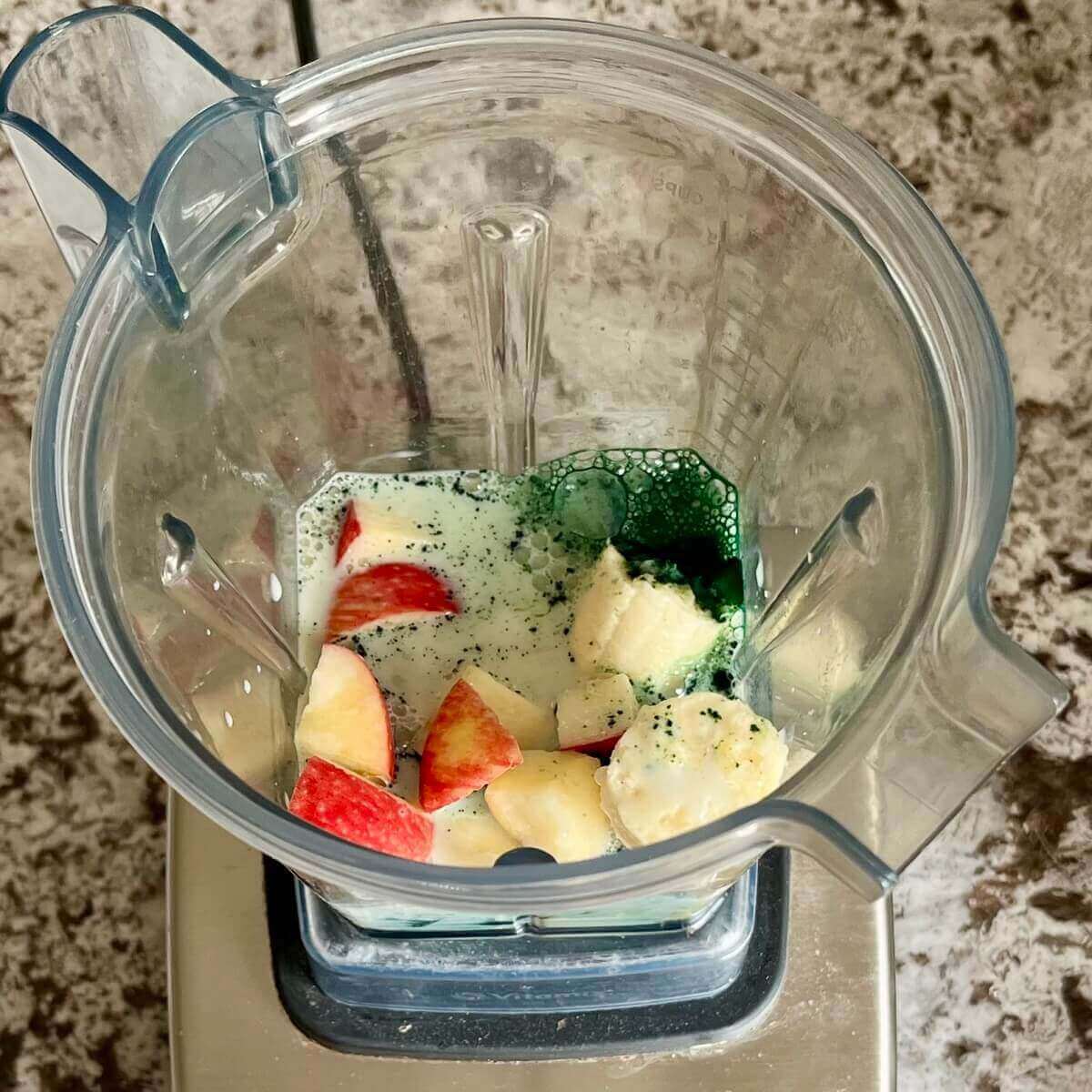 Spirulina powder, chopped apple, banana, vanilla, and soy milk in a blender.