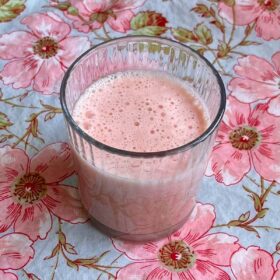 A watermelon lime smoothie in a glass on a floral cloth.