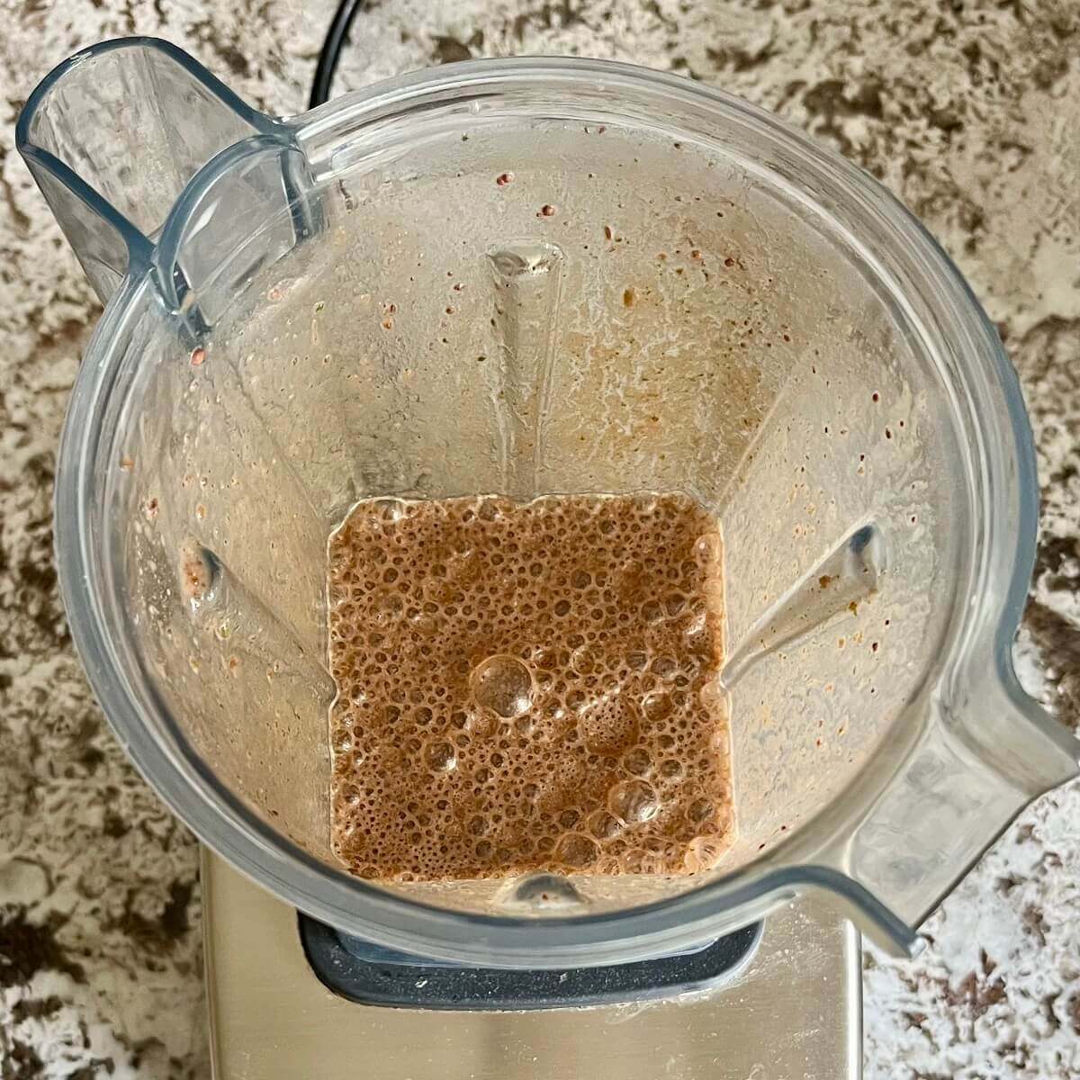 Mint, cocoa powder, and other ingredients for a smoothie blended in a blender.