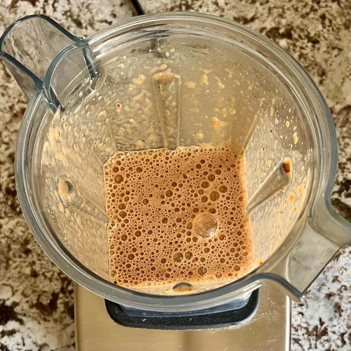 Blended orange, cocoa powder, a date, vanilla, sea salt, and soy milk in a blender.