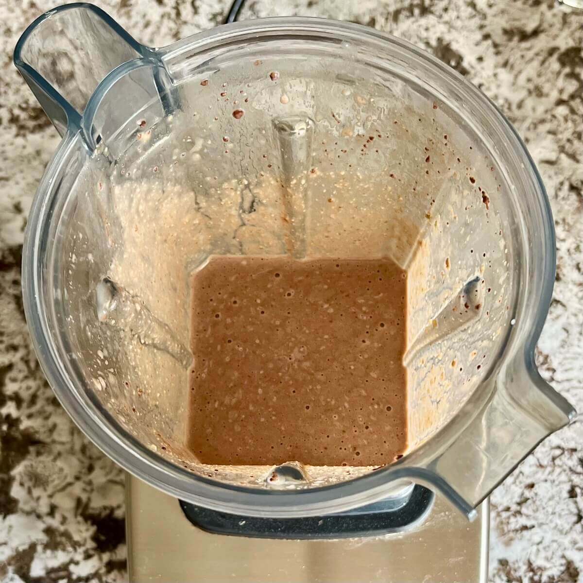 Pumpkin seeds and other ingredients for a smoothie blended in a blender.