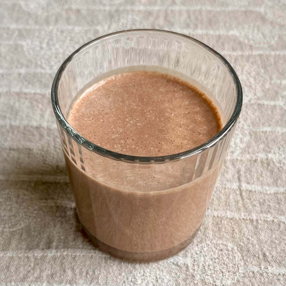A chocolate tahini smoothie in a glass.