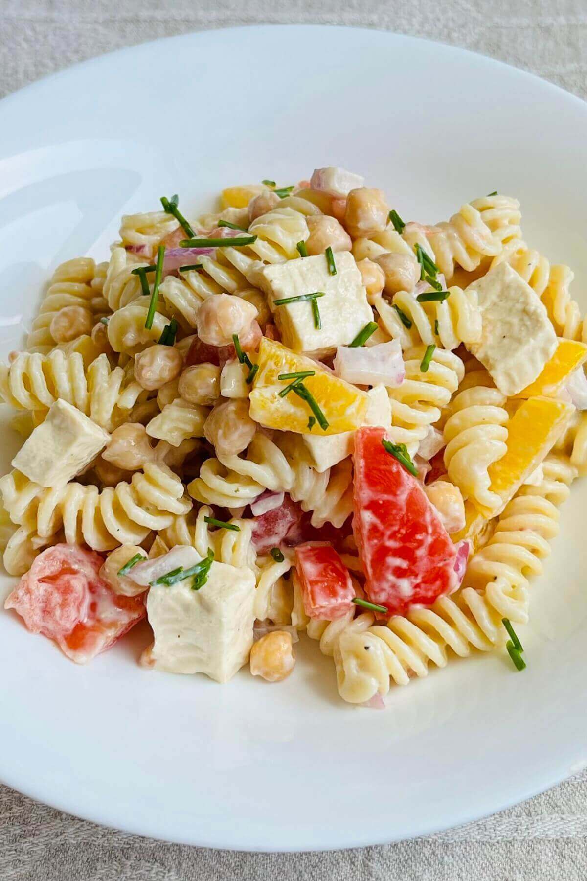 Pasta salad in a bowl on a beige cloth.