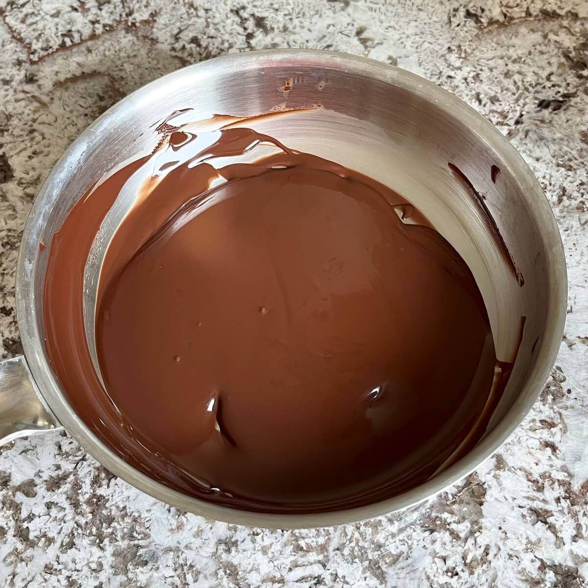 Melted dark chocolate in a stainless steel pan.