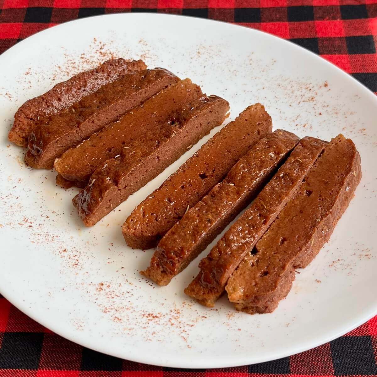 Sliced baked seitan on a white serving dish.