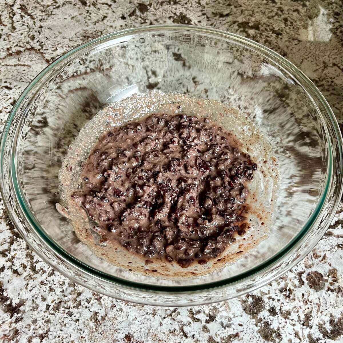 A mixture of mashed black beans and spices in a glass bowl.