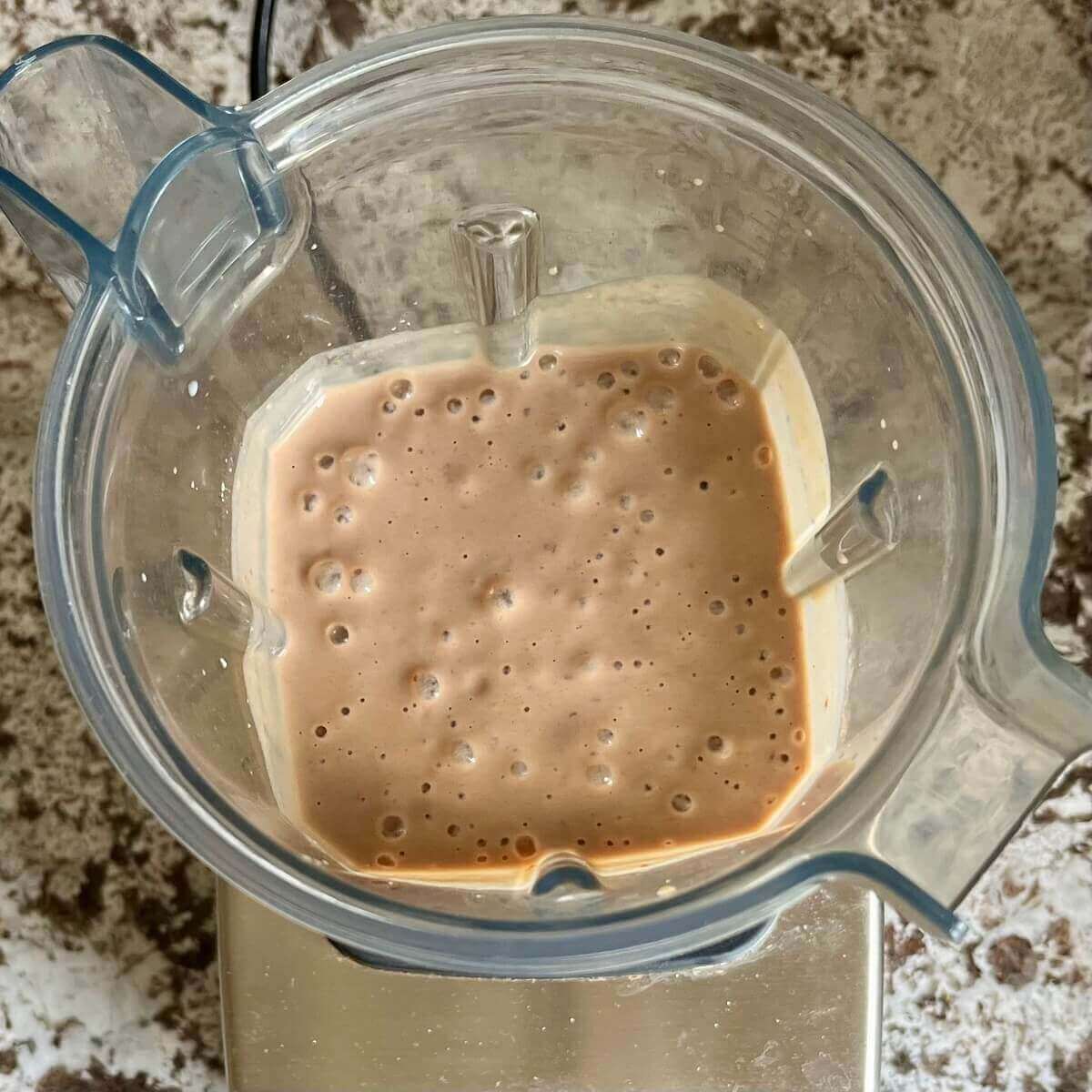 A creamy brown smoothie in a blender.