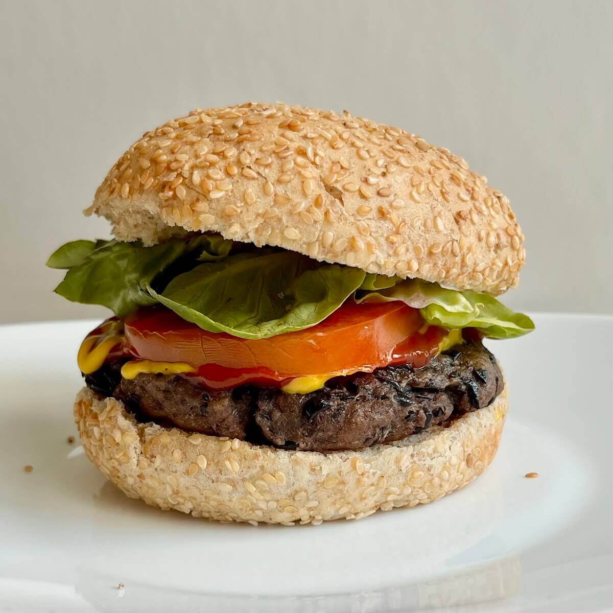 A high-protein black bean burger topped with lettuce, tomato, ketchup, and mustard on a sesame seed bun.
