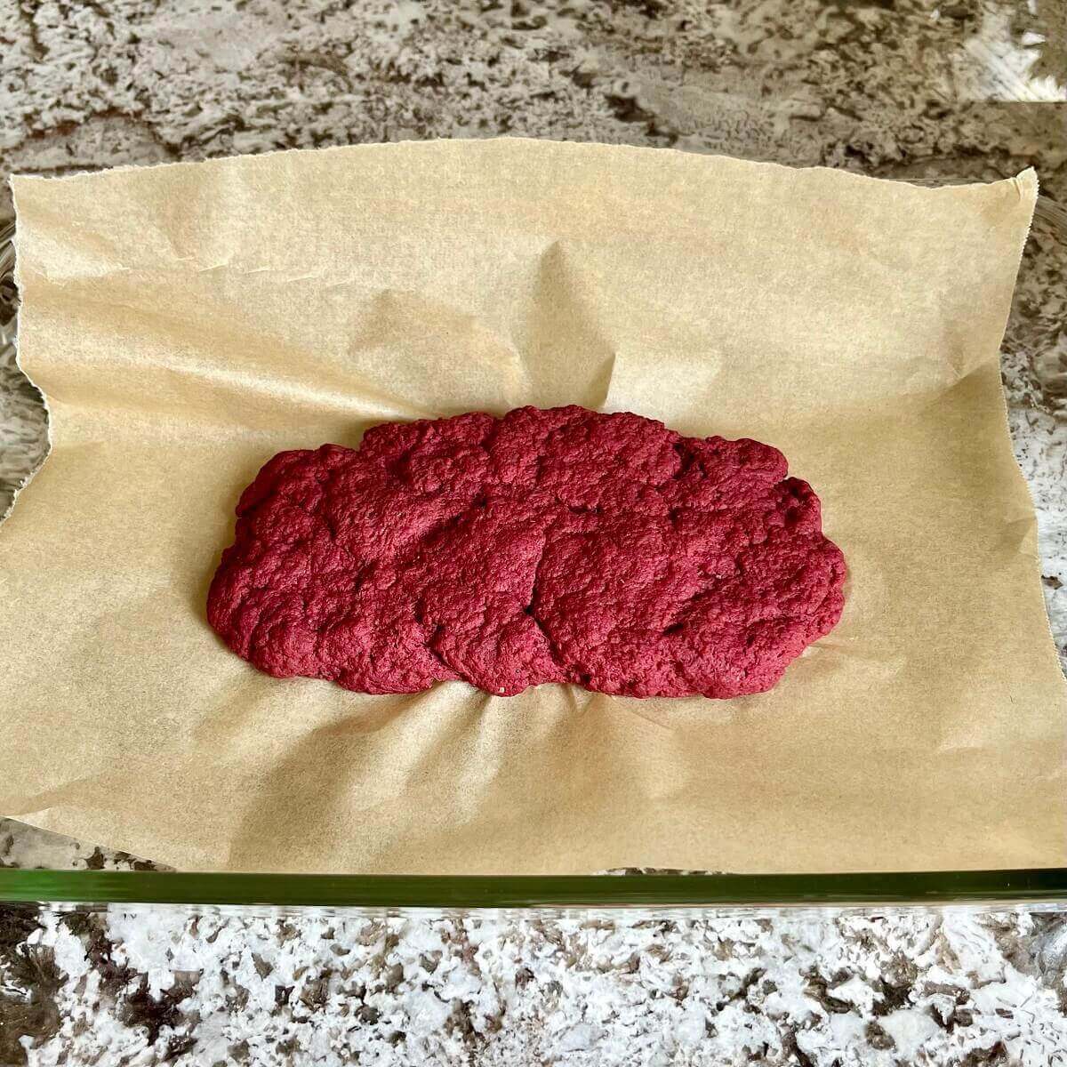 Raw pastrami dough in a baking dish lined with parchment paper.