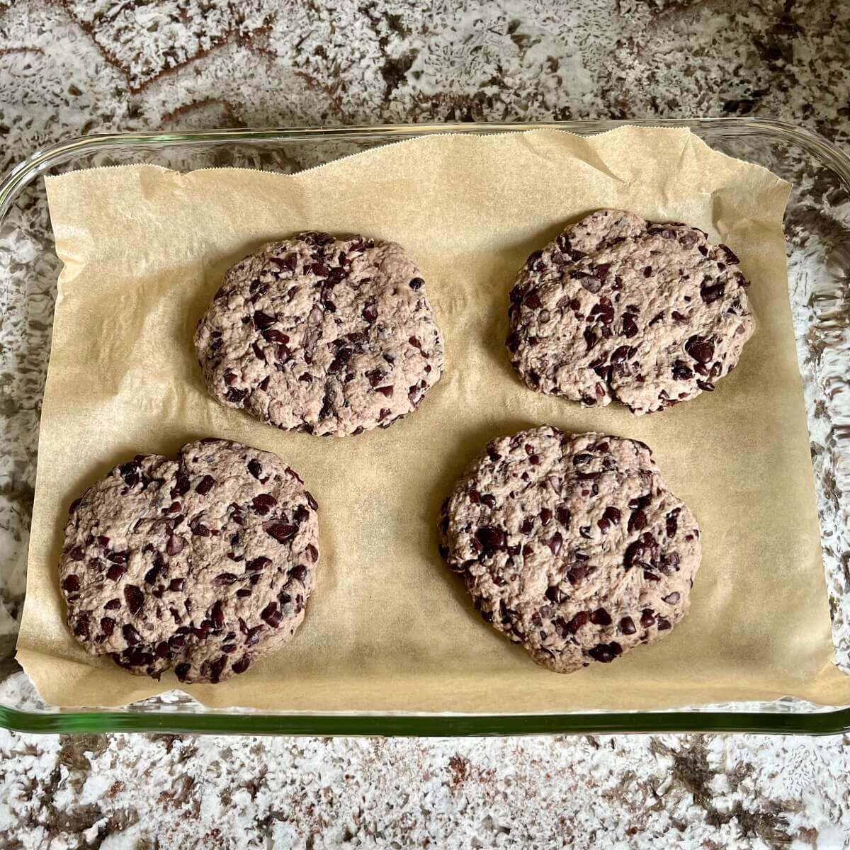 Uncooked vegan burger patties in a baking dish lined with parchment paper.