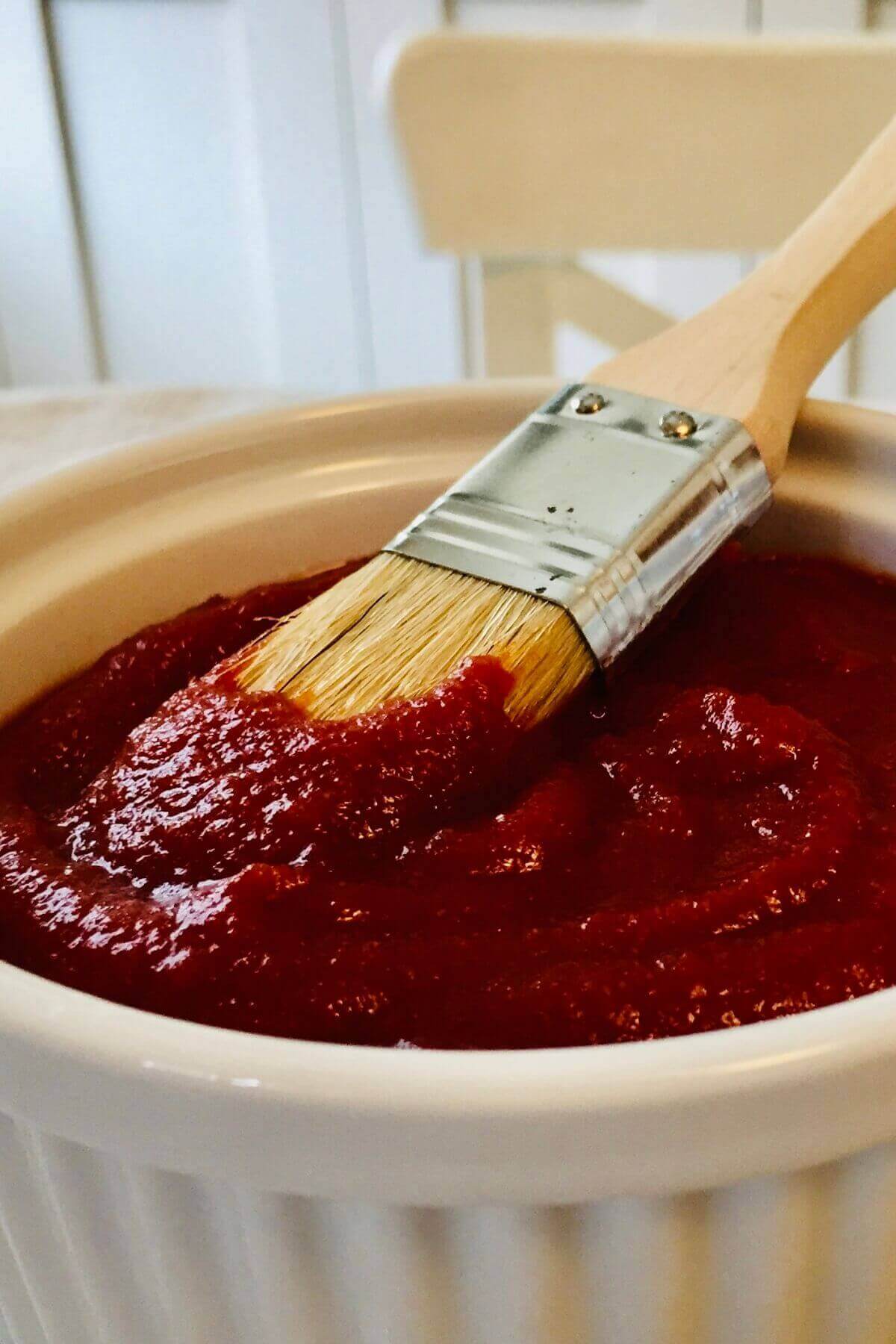 Date barbecue sauce in a white dish with a basting brush.