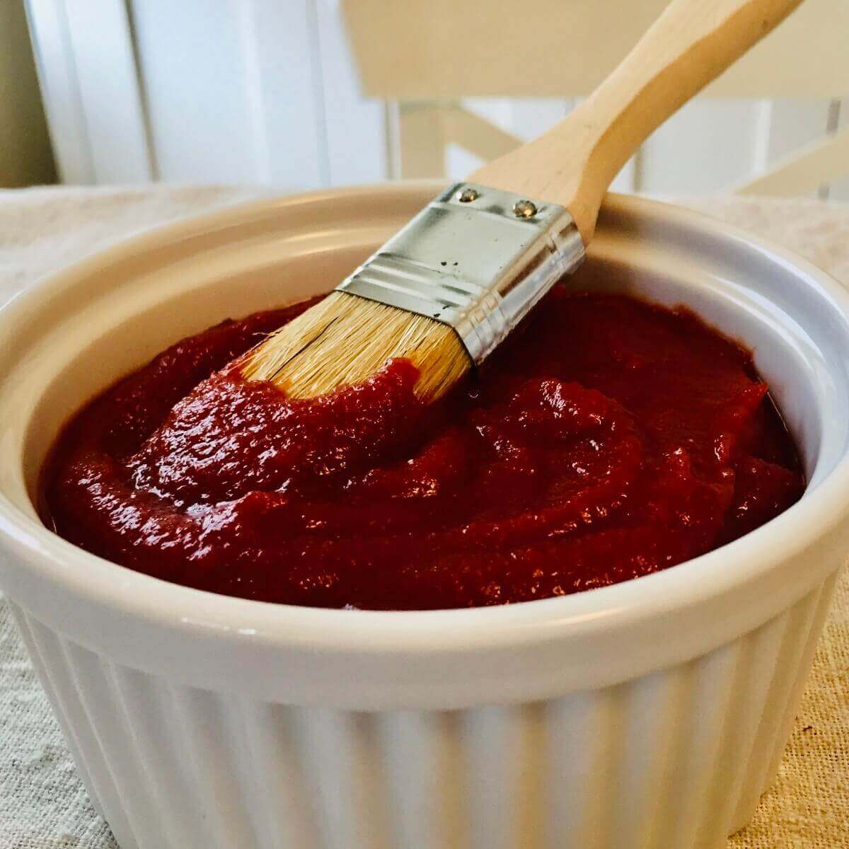 Homemade Paleo BBQ sauce in a white dish with a brush.