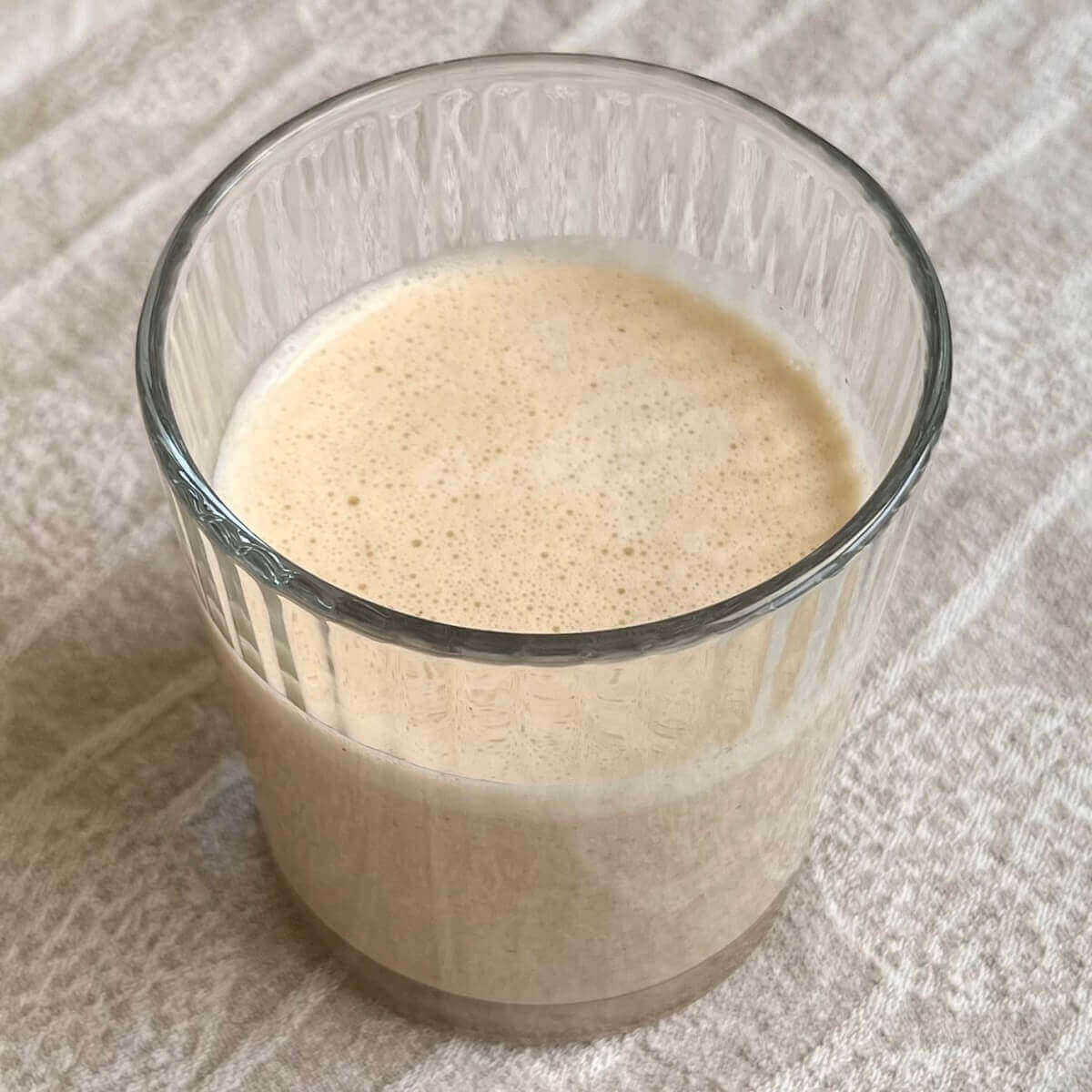 A salted caramel smoothie in a glass on a beige cloth.