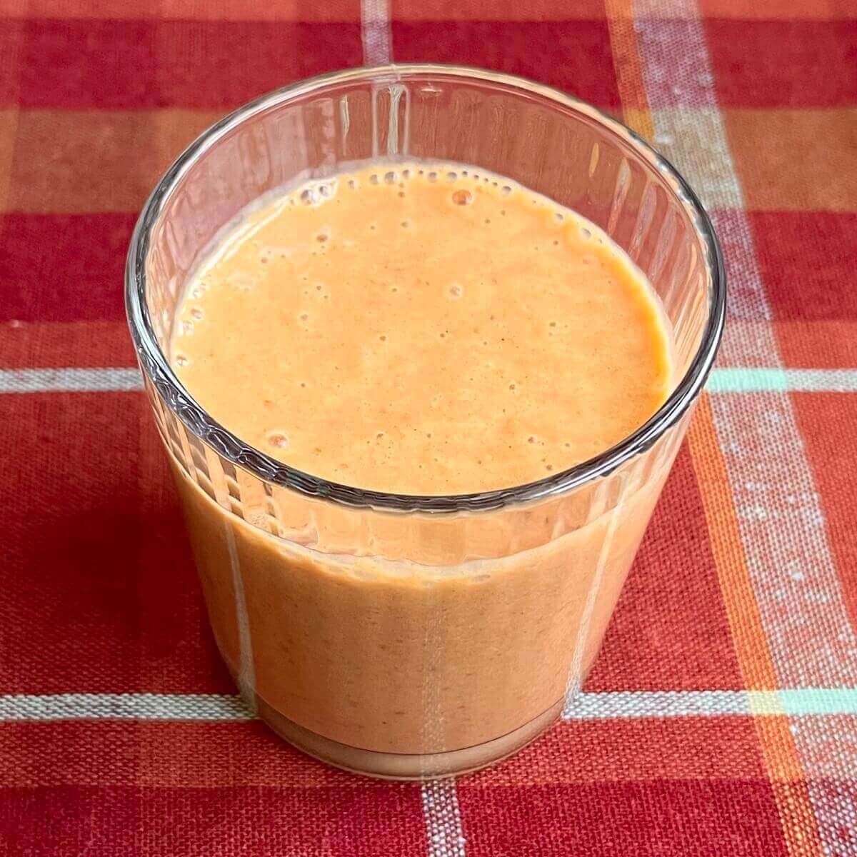 A creamy pumpkin spice fall smoothie in a glass.