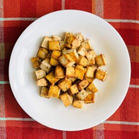 Thanksgiving tofu in a bowl on an orange plaid placemat.