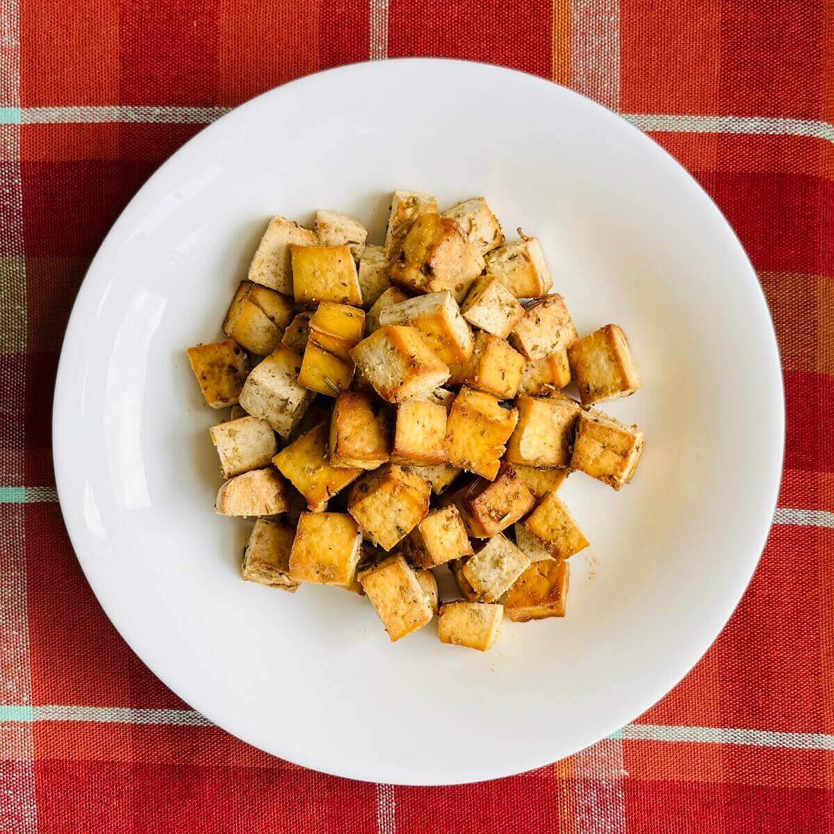 Thanksgiving tofu in a bowl on an orange plaid placemat.