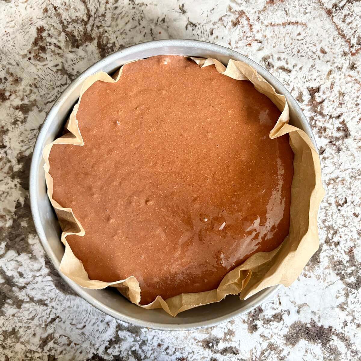 Cake batter in a round baking pan.