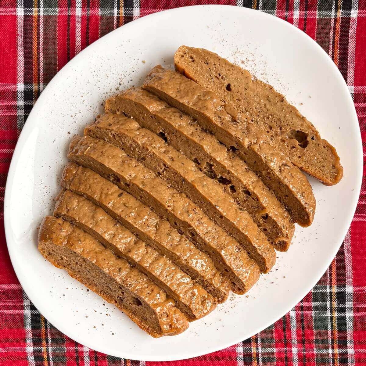 A vegan Christmas roast sliced on a white plate.