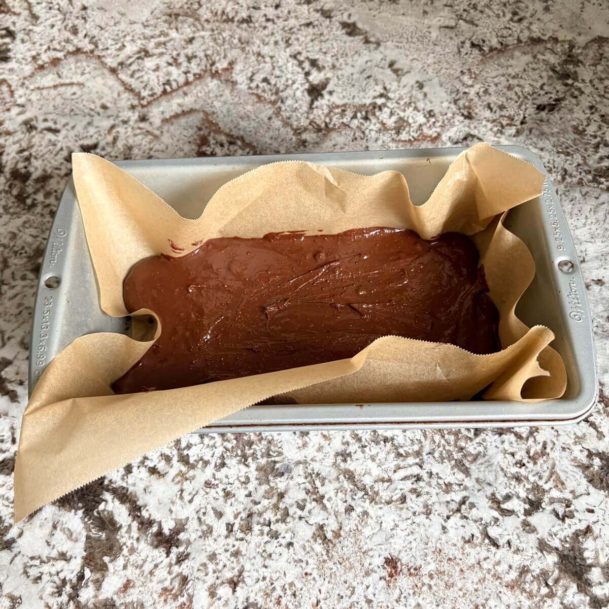 Raw fudge in a loaf pan lined with parchment paper.