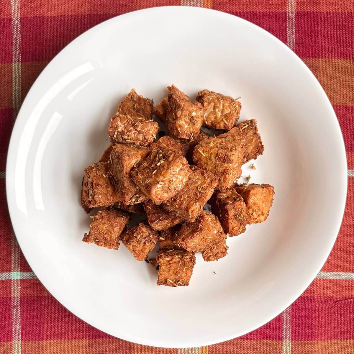 Marinated baked tempeh in a white bowl.