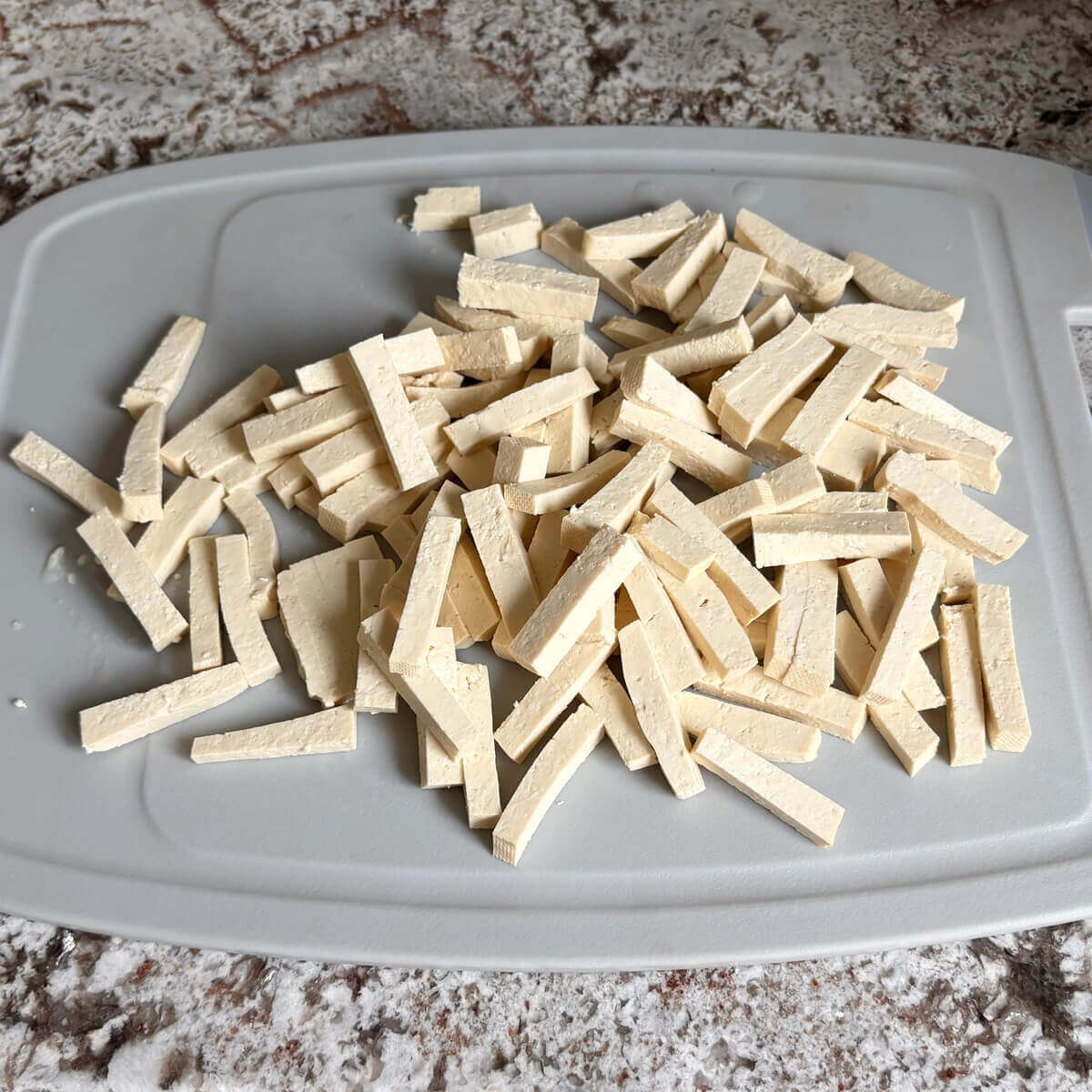 Short rectangular pieces of tofu on a cutting board.