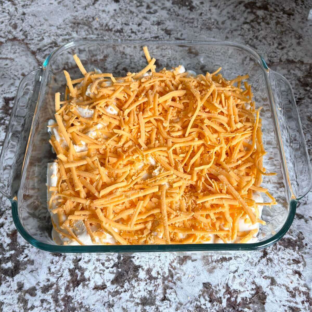 Unbaked vegan mac in a square glass baking dish.