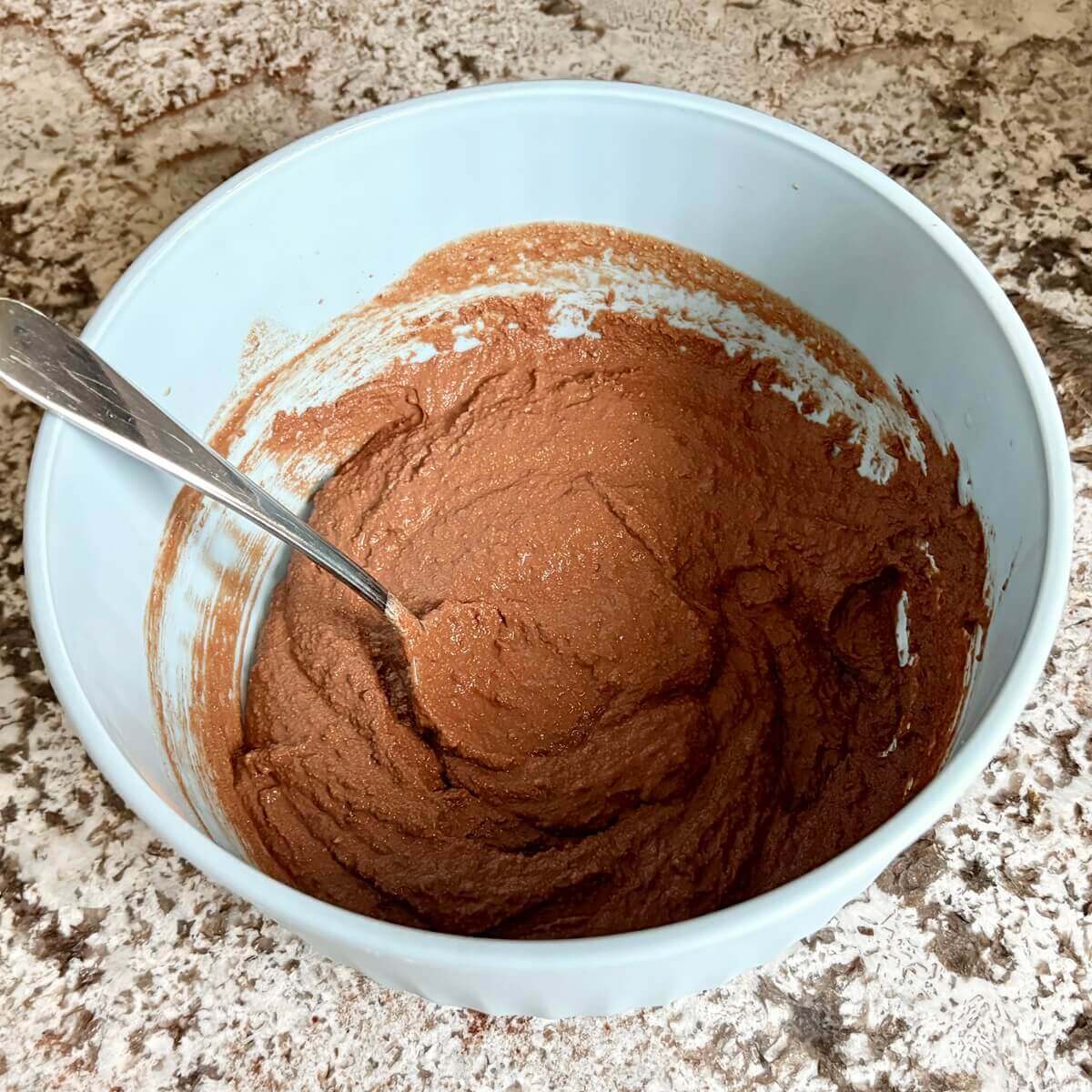 A thick cake batter made with monk fruit sweetener in a blue mixing bowl.