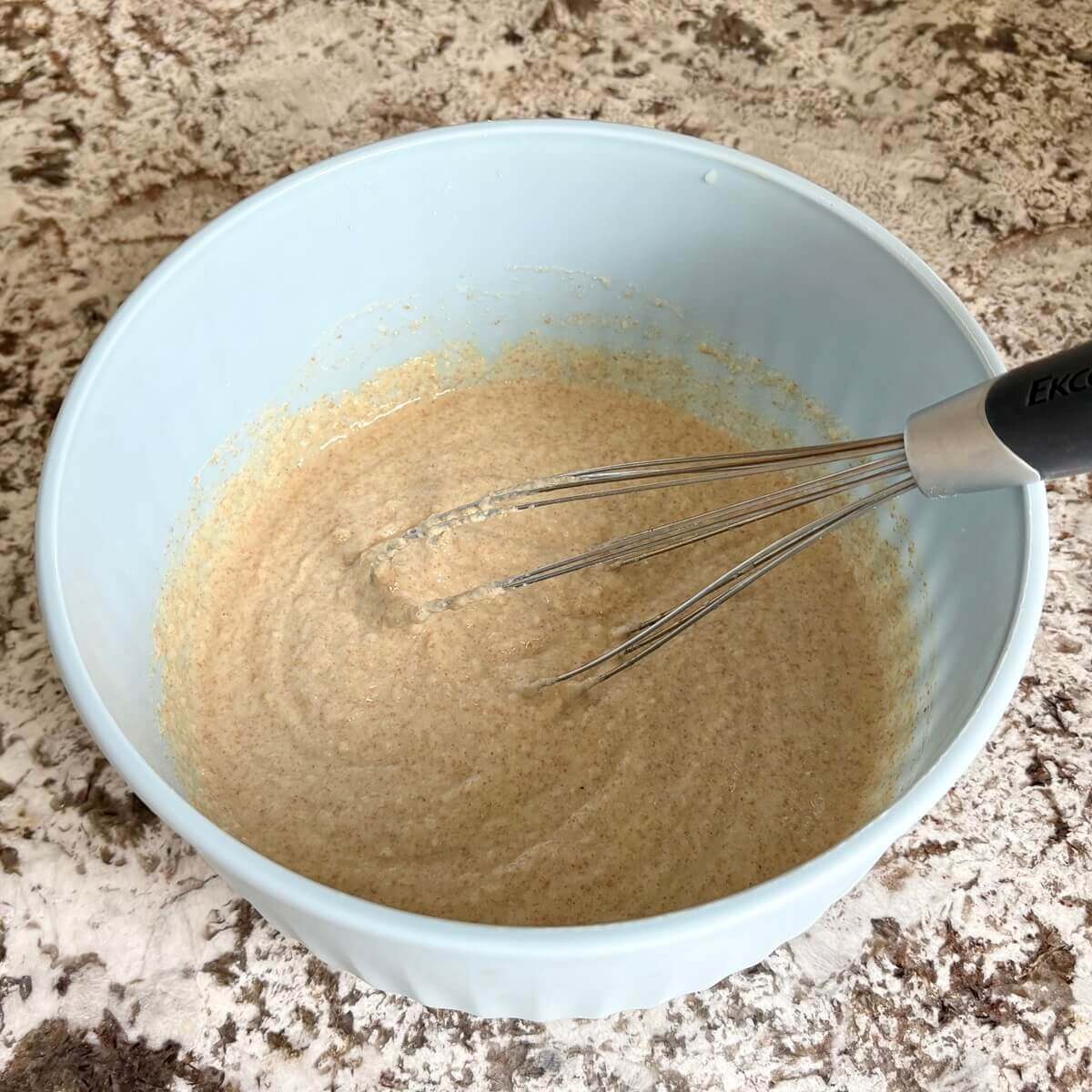Corn flour batter being whisked in a blue mixing bowl.