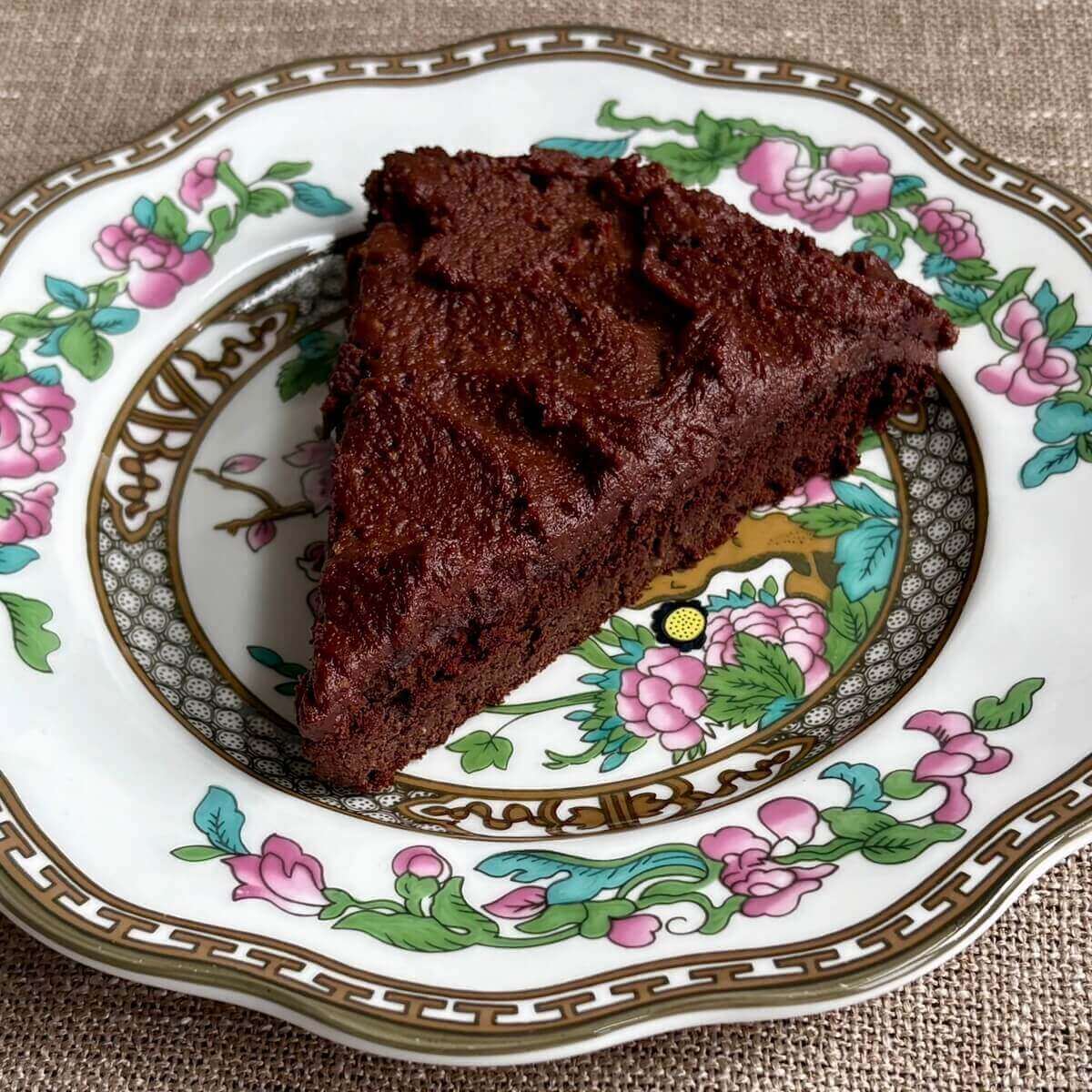 A slice of chocolate cake with monk fruit frosting on a plate.