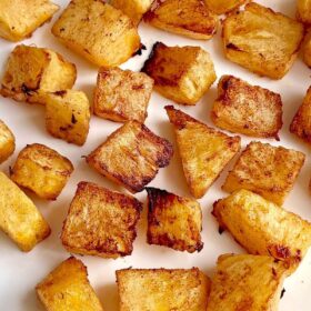 Pieces of oven-roasted pineapple on a white plate.
