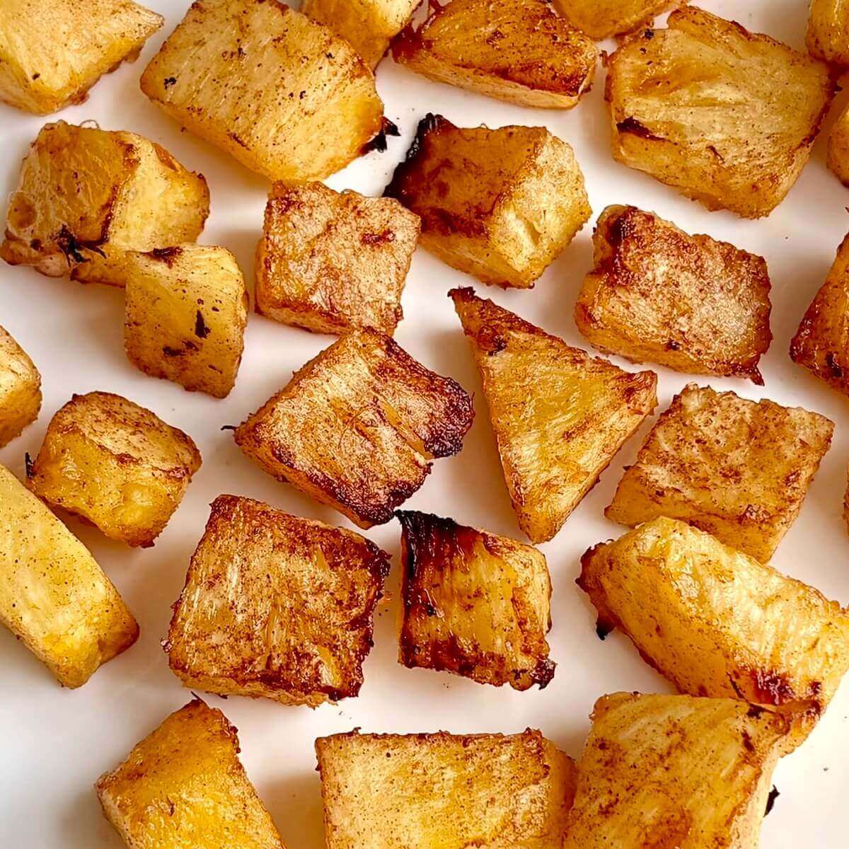 Pieces of oven-roasted pineapple on a white plate.
